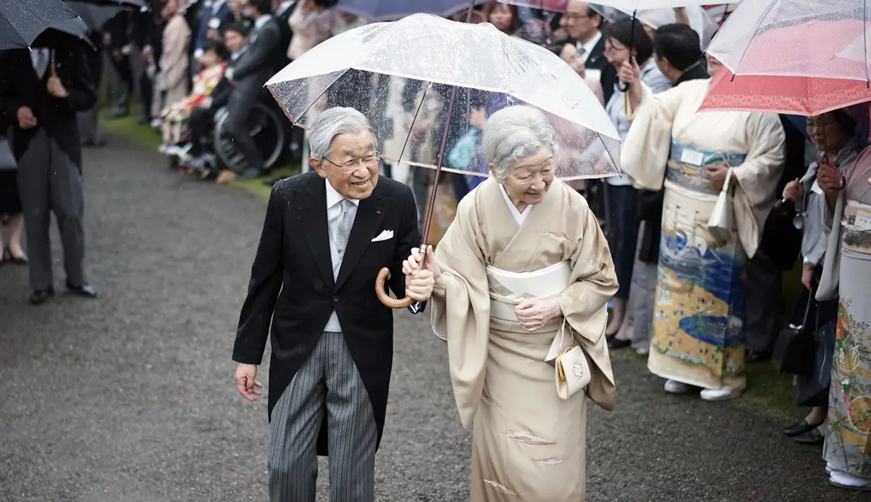 Kaisar Jepang Akihito dan Permaisuri Michiko menyambut para tamu saat pesta taman musim gugur di taman kekaisaran Akasaka Palace, Tokyo, Jumat (9/11). Kaisar dan Permaisuri tampil romantis dengan sepayung berdua saat hujan. (AP Photo/Eugene Hoshiko)