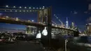 Gambar korban diproyeksikan pada Jembatan Brooklyn saat Hari Peringatan COVID-19 di Brooklyn, New York, Amerika Serikat, 14 Maret 2021. Kota New York yang mencatat kematian tertinggi akibat COVID-19 di AS, memberikan penghormatan yang emosional pada para korban yang meninggal. (Kena Betancur/AFP)