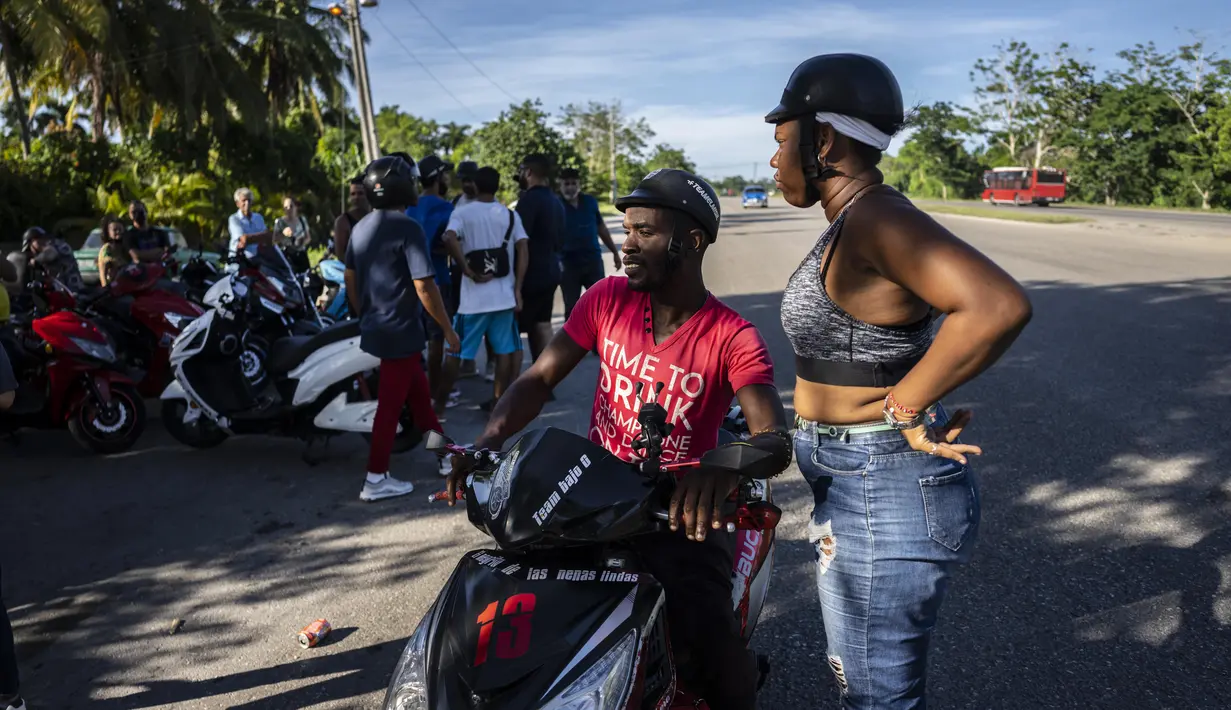 <p>Skuter listrik berkumpul di pinggir jalan untuk menghabiskan sore hari memamerkan aksi dan balapan di Havana, Kuba, pada 15 Juli 2022. Kuba telah dibanjiri dalam beberapa tahun terakhir dengan "motorinas", begitu skuter listrik ini disebut di pulau itu, sebuah mode bagi banyak orang, tetapi juga solusi untuk masalah transportasi dan kekurangan bahan bakar yang melanda negara Karibia itu. (AP Photo/Ramon Espinosa)</p>