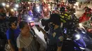 Polisi memeriksa suhu tubuh warga di pos pemeriksaan virus corona COVID-19 di Manila, Filipina, Senin (16/3/2020). Polisi beserta petugas lalu lintas dan petugas desa melakukan pengecekan suhu tubuh warga untuk mencegah penyebaran virus corona COVID-19. (AP Photo/Aaron Favila)