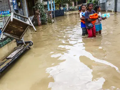 Sejumlah anak perempuan melintasi banjir yang masih merendam komplek Pondok Gede Permai, Jatiasih, Bekasi, Jumat (22/4). Sejak banjir menerjang perumahan tersebut hanya ada sekitar 50 warga yang mau dievakuasi. (Liputan6.com/Fery Pradolo)