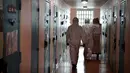 Seorang narapidana (kanan) yang mengenakan APD diawasi penjaga saat membagikan makanan siang kepada para tahanan di sel mereka sebagai bagian dari langkah-langkah mengekang penyebaran Covid-19 di pusat-pusat penahanan, di penjara Villepinte, dekat Paris, pada 6 Januari 2022. (ALAIN JOCARD/POOL/AFP)