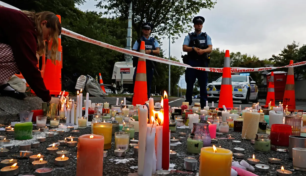 Seorang pelajar menyalakan lilin saat mengenang korban penembakan di luar Masjid Al Noor, Christchurch, Selandia Baru, Senin (18/3). Sebanyak 50 orang tewas dalam insiden tersebut. (AP Photo/Vincent Yu)