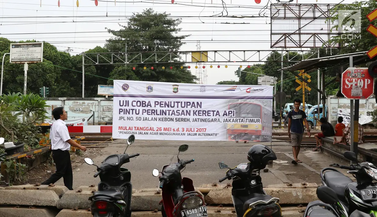 Pejalan kaki melintasi jalur uji coba penutupan pintu perlintasan sebidang kereta api di Jalan Kebon Sereh, Jatinegara, Jakarta Timur, Senin (29/5). Uji coba penutupan dilakukan pada 26 Mei - 3 Juli 2017. (Liputan6.com/Immanuel Antonius)