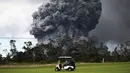 Kendaraan golf melintas saat kepulan asap abu vulkanik berembus dari puncak gunung Kiluaea di Big Island Hawaii (15/5). Kiluaea merupakan gunung berapi paling aktif di dunia. (AFP Photo/Mario Tama)