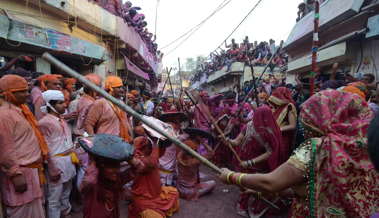 Sejumlah wanita memukul pria dengan tongkat (lathi) selama perayaan Lathmar Holi di Barsana di Mathura, India, (24/2). Lathmar Holi adalah perayaan lokal festival Hindu Holi, biasanya beberapa hari sebelum festival Holi. (AFP Photo/Dominique Faget)