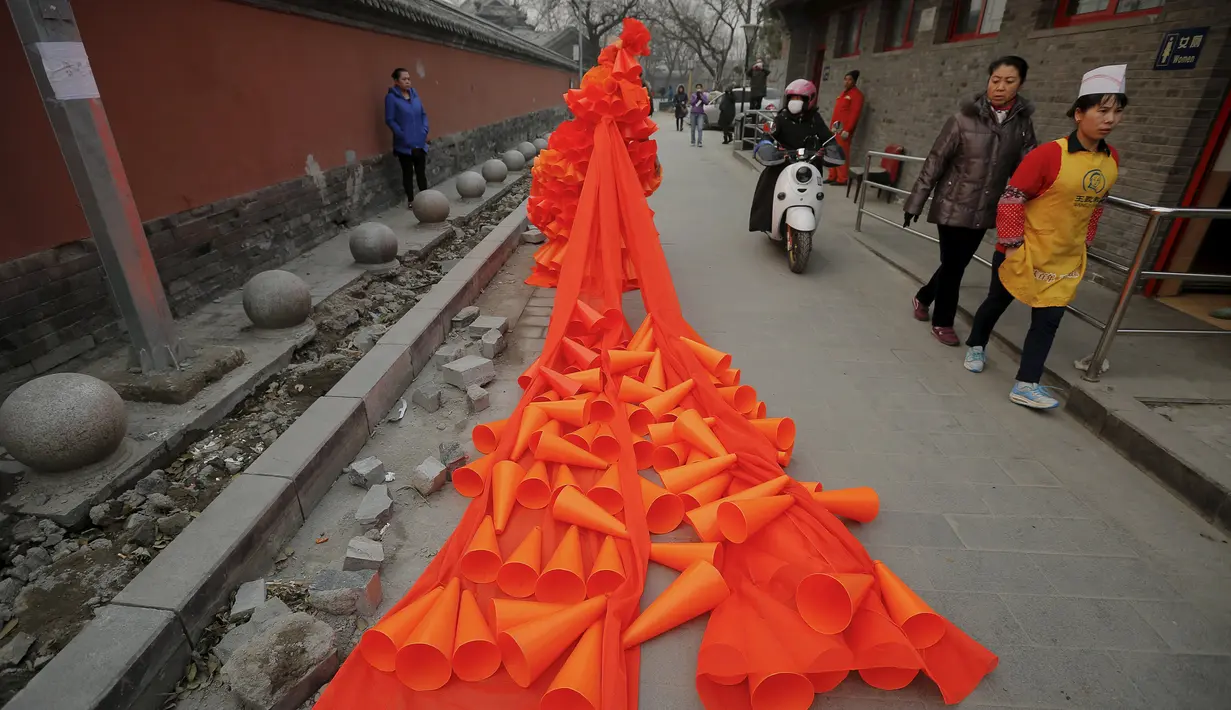 Seorang wanita mengenakan kostum dari plastik berbentuk kerucut selama protes yang dilakukannya di Beijing, Cina, (7/12). Ia menamakan karya kostumnya ini dengan judul "The Orange Horns Bride Marries the Blue Sky". (REUTERS/Damir Sagolj)