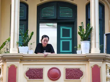 Gambar pada 3 September 2021 menunjukkan seorang perempuan melihat keluar dari balkon rumahnya di Hanoi, Vietnam, selama lockdown Covid-19. Menghadap ke jalan yang sepi, balkon kecil mereka menjadi saksi bisu terkait aktivitas yang dilakukan oleh masing-masing keluarga. (Nhac NGUYEN/AFP)