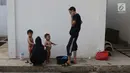Para pencari suaka memandikan anak-anaknya di halaman bekas Markas Kodim di kawasan Kalideres, Jakarta, Selasa (16/7/2019). Rata-rata para pencari suaka tersebut berasal dari Afghanistan, Pakistan, Somalia, Sudan, Iraq, dan Iran. (Liputan6.com/Helmi Fithriansyah)