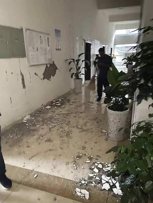 Orang-orang menyapu puing-puing di lorong gedung perkantoran setelah gempa bumi di Luzhou di Provinsi Sichuan, China barat daya (16/9/2021). Survei Geologi AS menempatkan besarnya gempa bermagnitudo 5,4. Namun Pusat Jaringan Gempa China mengukurnya pada kekuatan magnitudo 6,0. (Qiu Xin via AP)