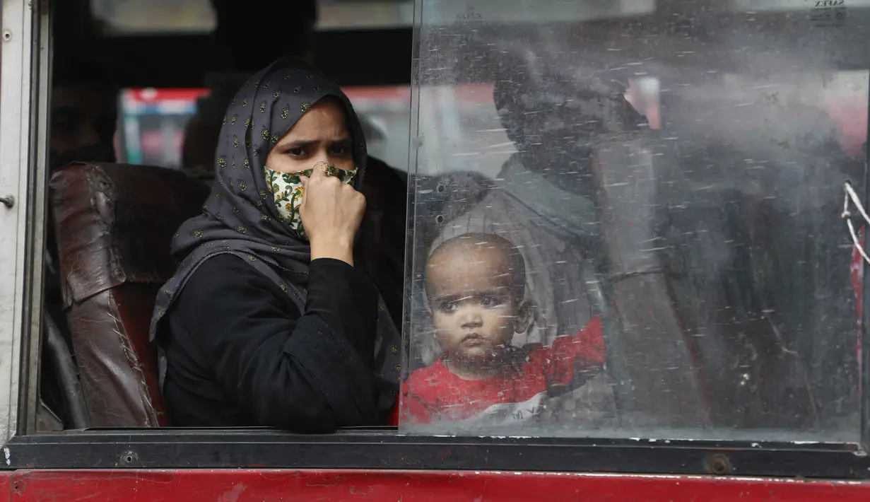 Seorang perempuan dan anak melihat ke luar jendela bus saat mereka berangkat menuju desanya setelah lockdown diberlakukan di ibu kota India, New Delhi, Selasa (20/4/2021). India melaporkan 259.170 infeksi baru dan 1.761 kematian akibat Covid-19 dalam 24 jam terakhir. (AP Photo/Manish Swarup)