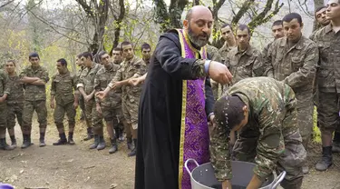 Pendeta Aristakes Hovhannisyan membaptis tentara Armenia di sebuah kamp militer dekat garis depan konflik di wilayah separatis Nagorno-Karabakh, Azerbaijan, Senin (2/11/2020). Pasukan Armenia dan Azerbaijan saling menyalahkan atas serangan baru selama perebutan Nagorno-Karabakh. (AP Photo)