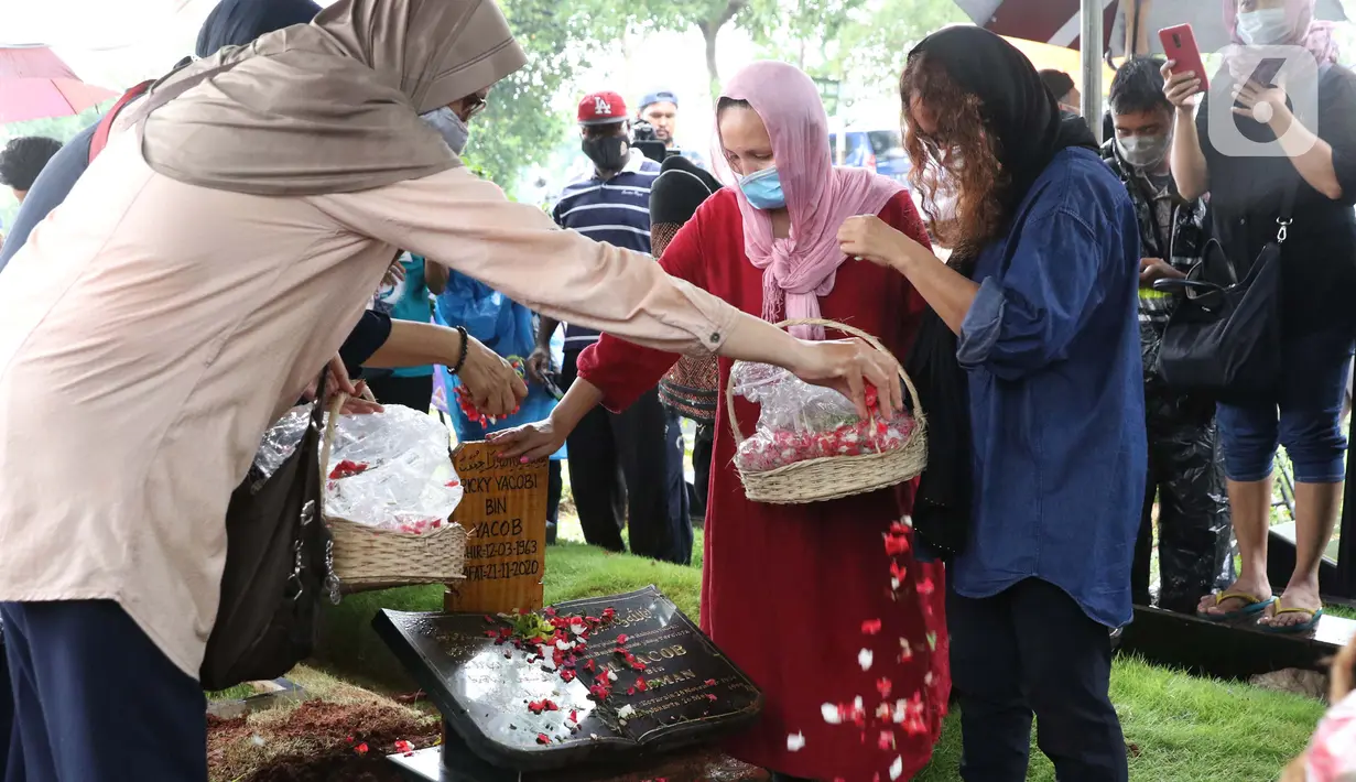 Istri mantan penggawa Timnas Indonesia Ricky Yacobi, Harly Ramayani (kanan) menabur bunga usai proses pemakaman suaminya di TPU Tanah Kusir, Jakarta, Sabtu (21/11/2020). Ricky Yacobi meninggal dunia pada Sabtu (21/11) akibat serangan jantung pada usia 57 tahun. (Liputan6.com/Helmi Fithriansyah)