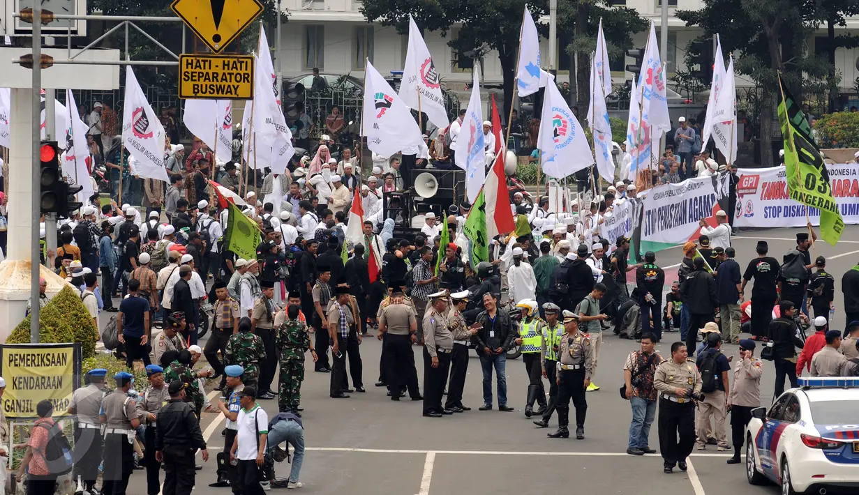 Aparat kepolisian mengawal aksi massa damai di Bundaran Patung Arjuna Wijaya, Jakarta, Jumat (4/11). Massa berkumpul untuk melakukan aksi di depan Istana Negara menuntut penegakan hukum kasus dugaan penistaan agama. (Liputan6.com/Helmi Fithriansyah)