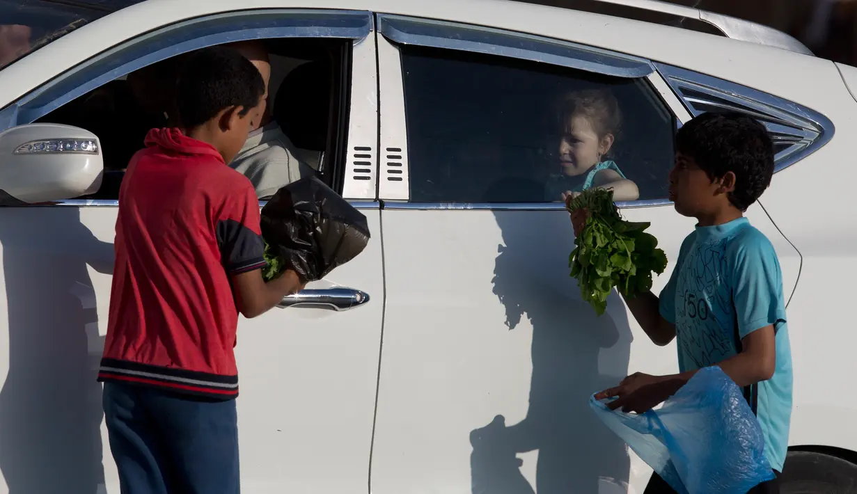 Anak-anak Palestina menjual sayuran untuk membantu keluarga mereka menghasilkan sedikit uang selama bulan suci Ramadhan di Gaza (19/5/2019). Umat Muslim di seluruh dunia tengah melaksanakan puasa dimana mereka tidak makan, minum mulai dari matahari terbit hingga terbenam. (AP Photo/Hatem Moussa)