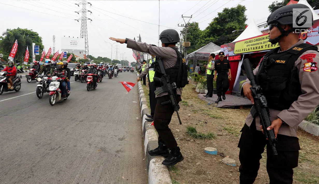 Polisi bersenjata berjaga sambil mengatur lalu lintas di jalur pantura Jenderal Ahmad Yani, Bypass, Kota Cirebon, Kamis (22/6). Selama arus mudik, pasukan bersenjata lengkap diterjunkan untuk mengantisipasi gangguan keamanan.  (Liputan6.com/Johan Tallo)