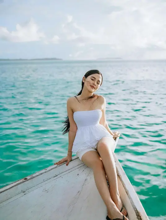 Bella Bonita terlihat bergaya di ujung perahu kayu mengenakan outfit serba putih. [Foto: Instagram/bellabonita_r.a]