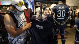Suporter Paris Saint-Germain memeriksa jersey bertuliskan nama Lionel Messi di toko resmi PSG, di Paris, Rabu (11/8/2021). Penjualan jersey PSG dengan nama Messi dan nomor punggung 30 laris manis, bahkan fans rela antre panjang. (AP Photo/Francois Mori)