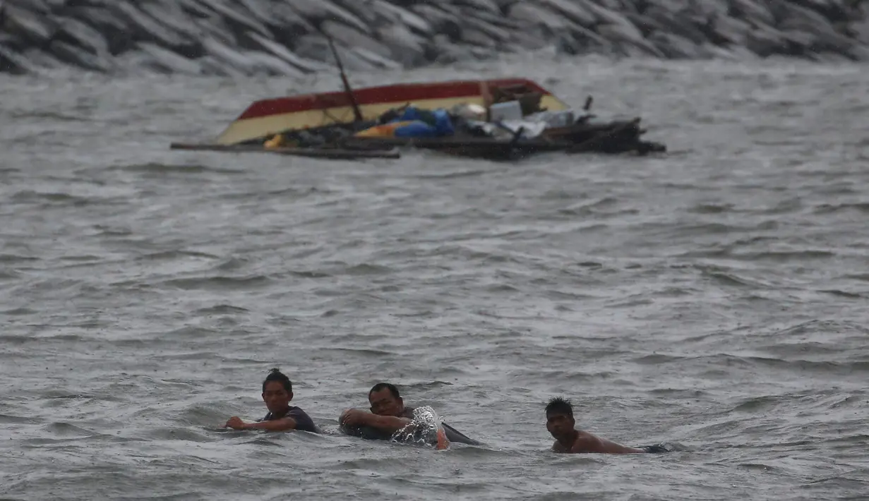 Tiga orang nelayan berusaha berenang ke darat setelah perahu mereka terbalik akibat Topan Nepartak yang menerpa Manila Bay, Filipina, Jumat (8/7). (REUTERS/Erik De Castro)
