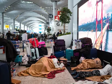 Penumpang yang terdampar menunggu di bandara Istanbul, di mana penerbangan dibatalkan karena badai salju dan hujan salju lebat, di Istanbul, Turki, pada 25 Januari 2022. Penutupan salah satu bandara tersibuk di Eropa ini akibat hantaman badai salju yang menghambat operasional. (Yasin AKGUL/AFP)