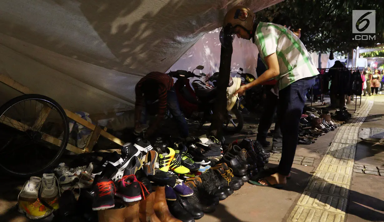 Calon pembeli melihat dagangan PKL di trotoar Jalan Sudirman di Kawasan Bendungan Hilir, Jakarta Pusat, Selasa (30/1). Berbagai dagangan mulai dari sepatu, baju, aksesoris, jam tangan dan lainnya dijajakan oleh mereka. (Liputan6.com/JohanTallo)