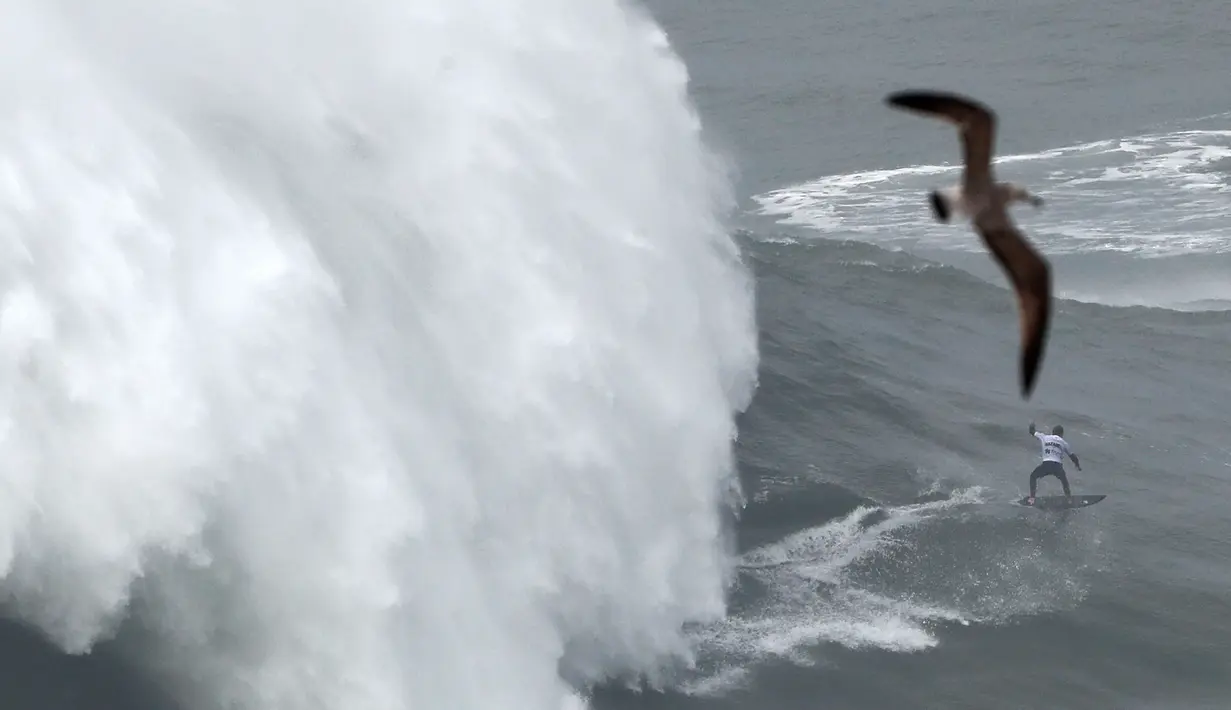 Peselancar Jerman Sebastian Steudtner berusaha menaklukkan ombak Praia do Norte atau Pantai Utara di Nazare, Portugal, Selasa (11/2/2020). Hanya peselancar profesional yang boleh bermain ombak di perairan ini. (AP Photo/Armando Franca)