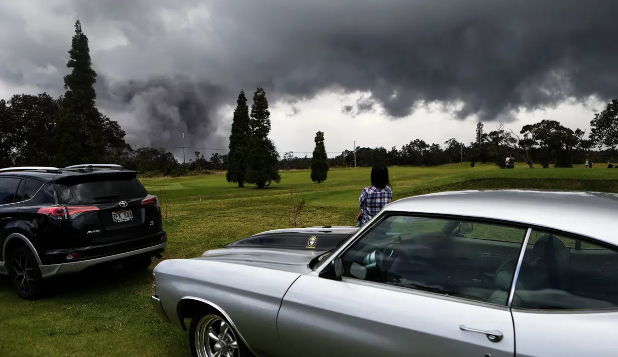 Seorang wanita melihat asap tebal yang berembus dari puncak gunung berapi Kilauea di Hawaii. 15 Mei 2018. Para wisatawan tetap santai dan justru menjadikan letusan gunung ini sebagai objek wisata. (MARIO TAMA/GETTY IMAGES NORTH AMERICA/AFP)