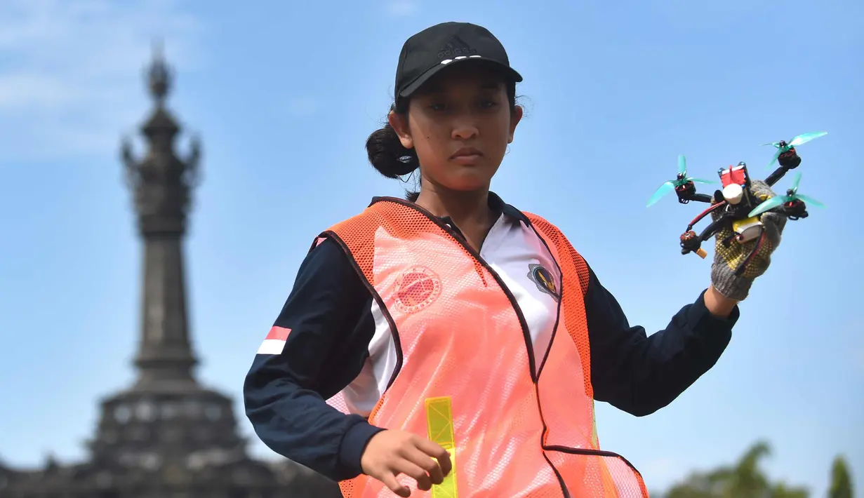 Seorang wanita bersiap menerbangkan drone balap selama acara Piala Dunia FAI Drone Racing di Denpasar di pulau resor Indonesia Bali (7/4). Acara ini diselenggarakan dalam rangka HUT ke-72 TNI-AU dan Bulan Dirgantara 2018. (AFP Photo/Sonny Tumbelaka)