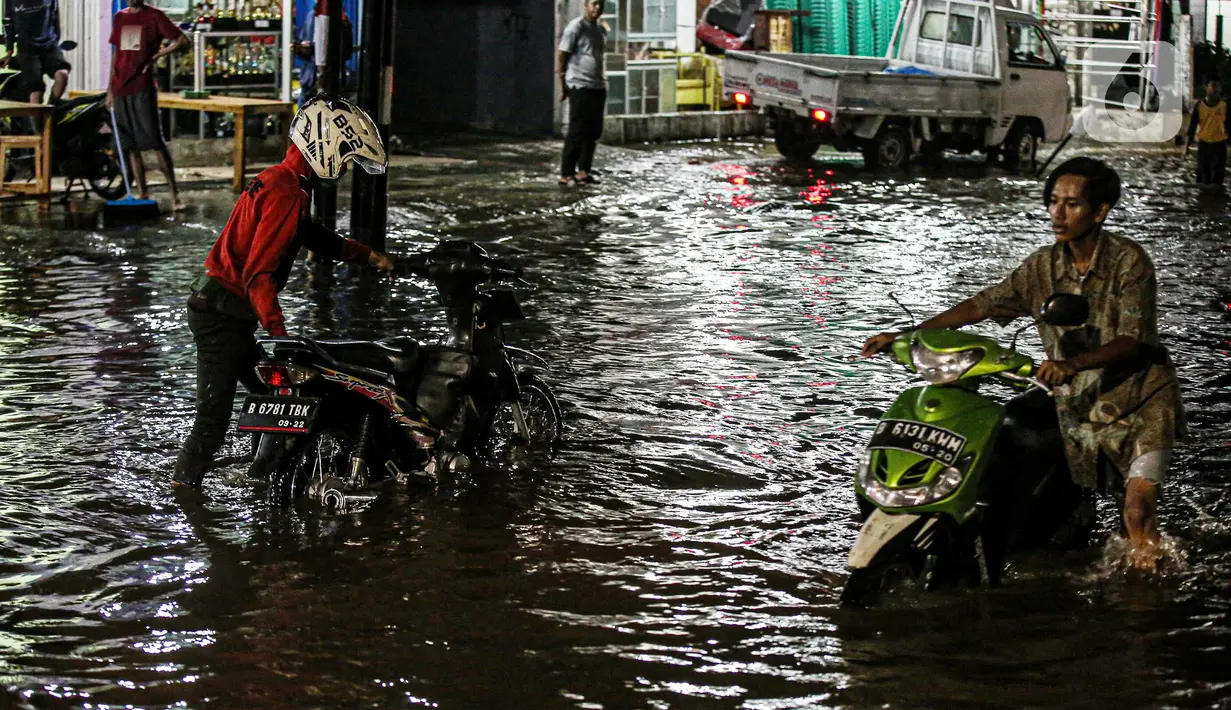 Pengendara sepeda motor mendorong kendaraannya saat melewati banjir di Jalan Ciracas Raya, Jakarta, Jumat (12/8/2022). Hujan lebat yang terjadi sore tadi membuat Jalan Ciracas Raya tergenang air dan kendaraan terjebak banjir. (Liputan6.com/Faizal Fanani)