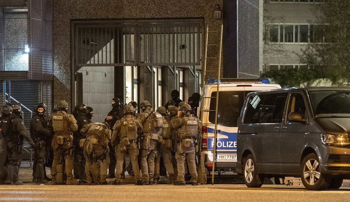 Petugas polisi bersenjata berkumpul di dekat lokasi penembakan di sebuah gedung yang digunakan gereja Saksi-Saksi Yehuwa di Hamburg, Jerman, Kamis (9/3/2023). Pihak kepolisian setempat pada Kamis malam mengatakan pelaku penembakan diduga termasuk di antara korban tewas, dan motifnya masih belum jelas.  (Daniel Bockwoldt/dpa via AP)