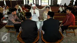 Reza Pahlevi dan Ika Nico saat berada di depan penghulu untuk dinikahkan, Masjid Al Ittihad, Jakarta, Jumat (28/8/2015). Reza menikahi Ika dengan mas kawin tiga buah cincin berlian dan seperangkat alat salat (Liputan6.com/Faisal R Syam)