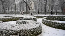 Orang-orang berjalan saat salju turun di Taman Retiro di pusat kota Madrid (7/1/2021). Spanyol dalam keadaan siaga cuaca untuk suhu dingin, es, hujan dan salju akibat Badai Filomena, yang diperkirakan akan melanda sebagian besar semenanjung Iberia dalam beberapa hari mendatang. (AFP/Gabriel Bouys)