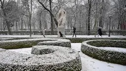 Orang-orang berjalan saat salju turun di Taman Retiro di pusat kota Madrid (7/1/2021). Spanyol dalam keadaan siaga cuaca untuk suhu dingin, es, hujan dan salju akibat Badai Filomena, yang diperkirakan akan melanda sebagian besar semenanjung Iberia dalam beberapa hari mendatang. (AFP/Gabriel Bouys)