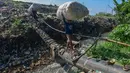 Warga menyebrangi Kali Pesanggrahan yang menyempit akbat longsoran timbunan sampah TPA Cipayung di kawasan Pasir Putih, Depok, Jawa Barat, Senin (27/04/2026), setelah longsoran sampah dari Tempat Pembuangan Akhir (TPA) Cipayung menutup sebagian badan sungai. (merdeka.com/Arie Basuki)