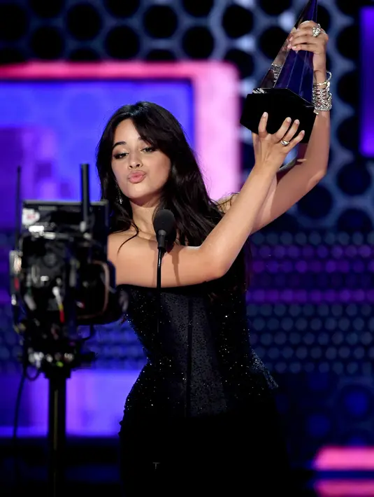 Penyanyi Camila Cabello mengangkat piala pertamanya pada ajang American Music Awards 2018 di Microsoft Theater, Los Angeles, Selasa (9/10). Lewat lagu 'Havana', Camilla dianugerahi sebagai Lagu Pop/Rock Terfavorit 2018. (Kevin Winter/Getty Images/AFP)