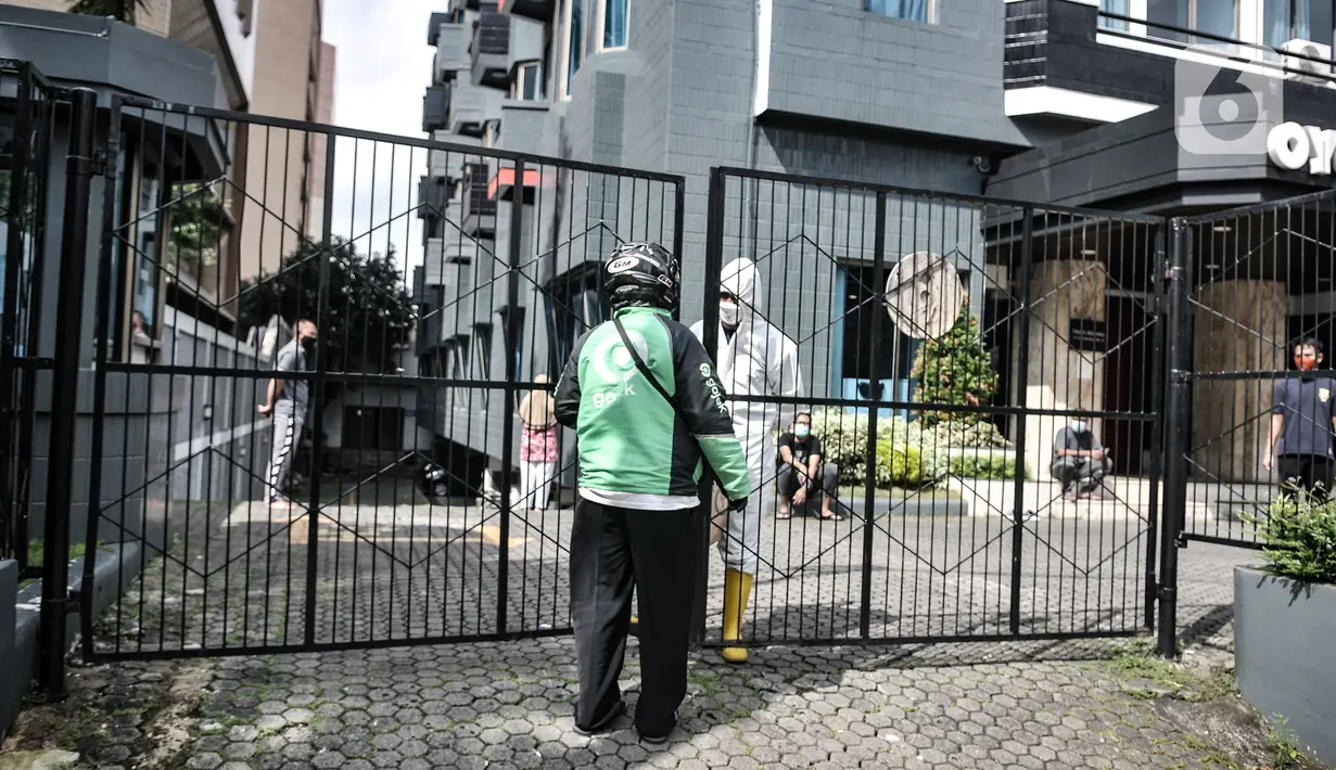 Petugas keamanan mengenakan baju hazmat saat menerima barang pesanan pasien di sebuah hotel kawasan Salemba, Jakarta, Senin (22/2/2021). Hotel masih menjadi pilihan warga di Jakarta sebagai tempat isolasi mandiri ketika terpapar virus Covid-19. (merdeka.com/Iqbal S. Nugroho)