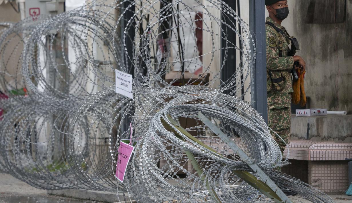 Tentara bersenjata berjaga di samping kawat berduri di kawasan Segambut Dalam yang ditempatkan di bawah perintah peningkatan kontrol gerakan (EMCO) karena peningkatan drastis jumlah kasus COVID-19 yang tercatat selama 10 hari terakhir di Kuala Lumpur, Malaysia (27/6/2021). (AP Photo/Vincent Thian)