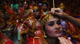 Seorang calon pengantin wanita dirias sebelum mengikuti upacara pernikahan massal di Kolkata, India (14/2). Acara nikah massal ini diselenggarakan oleh LSM setempat yang bertujuan untuk merayakan Hari Valentine. (AFP Photo/Dibyangshu Sarkar)