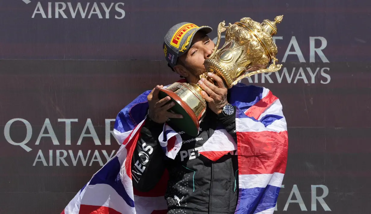 Pembalap Mercedes, Lewis Hamilton mencium piala saat merayakan kemenangannya di Formula 1 GP Inggris 2024 yang berlangsung di Sirkuit Silverstone, Inggris, Minggu (08/07/2024). (AFP/Benjamin Cremel)