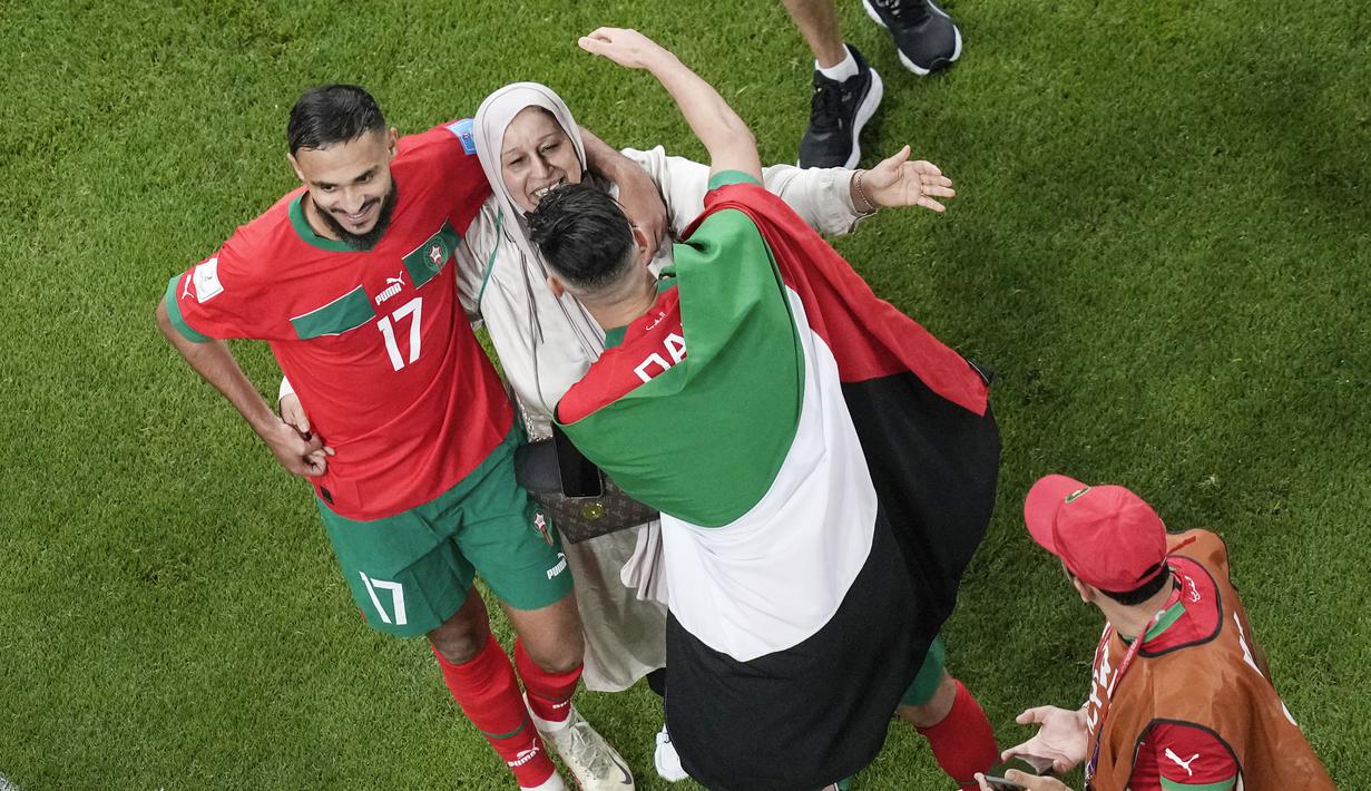 Pemain Maroko, Achraf Daria, merayakan kemenangan atas Portugal bersama keluarganya pada laga perempat final di Stadion Al-Thumama, Sabtu (10/12/2022). (AP/Thanassis Stavrakis)