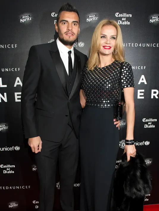 Kiper Manchester United, Sergio Romero (kiri) dan istrinya Eliana Guercio berpose di atas karpet merah saat mereka tiba untuk menghadiri "Inggris untuk UNICEF Gala Dinner" di Old Trafford, Manchester, Inggris, (29/11). (AFP PHOTO/OLI SCARFF)