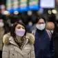 Seorang wanita memakai masker berjalan di stasiun Shinagawa di Tokyo (18/1/2022). Jepang melaporkan rekor tertinggi infeksi Covid-19 baru yang dipicu oleh varian Omicron. (AFP/Philip Fong)