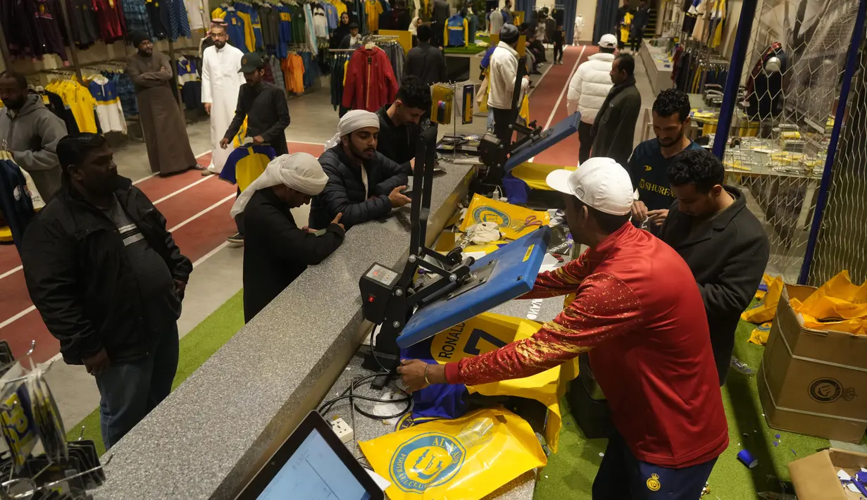 Pekerja mencetak kaus Cristiano Ronaldo di toko klub Al Nassr di Riyadh, Arab Saudi, Senin, 2 Januari 2023. Banyaknya permintaan yang membludak stok jersey Al Nassr di toko-toko bahkan hampir habis. Beberapa penggemar membawa jersey sendiri agar nama Ronaldo bisa tercetak di atasnya. (AP Photo/Amr Nabil)