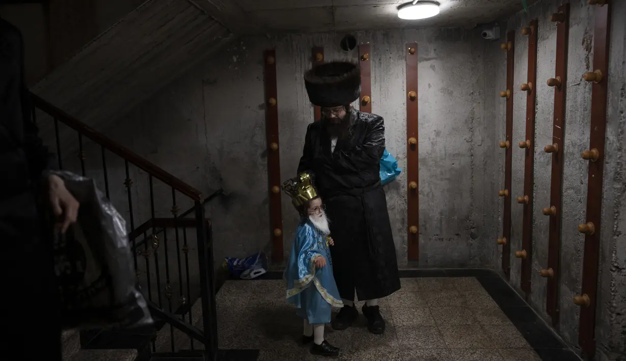 Seorang pria Yahudi ultra-Ortodoks dan putranya yang mengenakan kostum merayakan festival Yahudi Purim di sebuah sinagoga di Bnei Brak, Israel, Senin (6/3/2023). Purim tahun ini akan dimulai pada malam tanggal 6 Maret dan berlanjut hingga tanggal 7 Maret malam. (AP Photo/Oded Balilty)