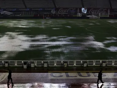 Tampak orang berjalan dipinggir lapangan yang banjir akibat hujan lebat di stadion Monumental, Argentina, Jumat (13/11/2015). Lapangan yang dipakai untuk Pertandingan antara Argentina dan Brasil dihentikan akibat kondisi ini. (REUTERS/Marcos Brindicci)