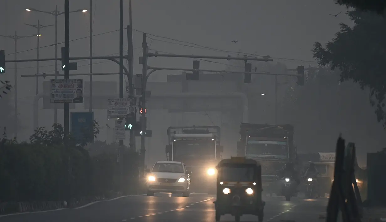 Kendaraan bermotor melintas di sepanjang jalan di tengah kondisi kabut asap yang menyelimuti New Delhi, India, Minggu (7/11/2021). Ibu kota New Delhi diselimuti udara beracun pada Sabtu kemarin karena tingkat polusi yang sangat tinggi pasca-perayaan festival besar agama Hindu. (Money SHARMA/AFP)