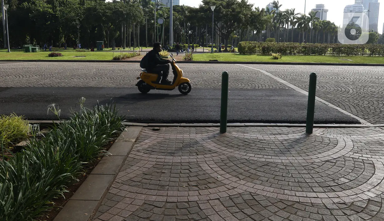 Pengunjung melewati contoh aspal lintasan Formula E di Monas, Jakarta, Minggu (23/2/2020). Aspal untuk sirkuit Formula E di uji coba di Monas, lokasi pengaspalan itu berada di Monas bagian timur. Pengaspalan dilakukan dengan dua metode, sandsheet dan geotextile. (Liputan6.com/Herman Zakharia)