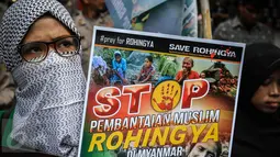 Massa yang mengatasnamakan Solidaritas Muslim Rohingya (SMR) membawa sebuah poster di depan Kedubes Myanmar, Jakarta, Jumat (25/11). Mereka menuntut pemerintah Myanmar segera menghentikan kekerasan terhadap muslim Rohingya. (Liputan6.com/Faizal Fanani)