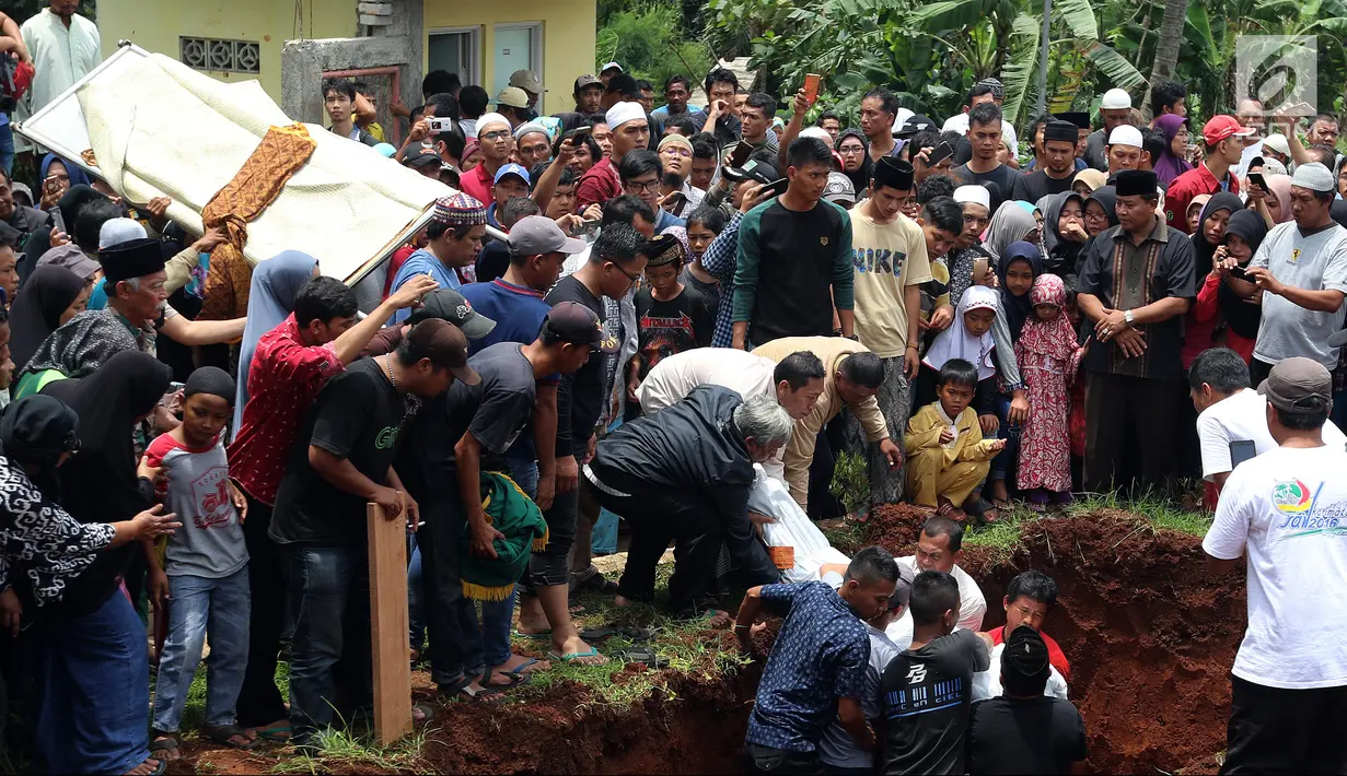 Penurunan jenazah ke liang lahat saat pemakaman korban kecelakaan bus di Tanjakan Emen Subang di TPU Legoso Ciputat, Tangerang Selatan, Banten, Minggu (11/2). Diduga, bus rombongan mengalami rem blong saat melewati Tanjakan Emen. (Liputan6.com/JohanTallo)