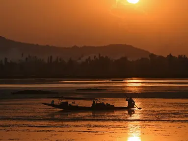 Seorang nelayan Kashmir mengayuh perahunya saat matahari terbenam di danau Dal di Srinagar, India (12/9). Danau Dal dijuluki sebagai Jewel in the Crown of Kashmir atau Srinagar Jewel. (AFP Photo/Tauseef Mustafa)